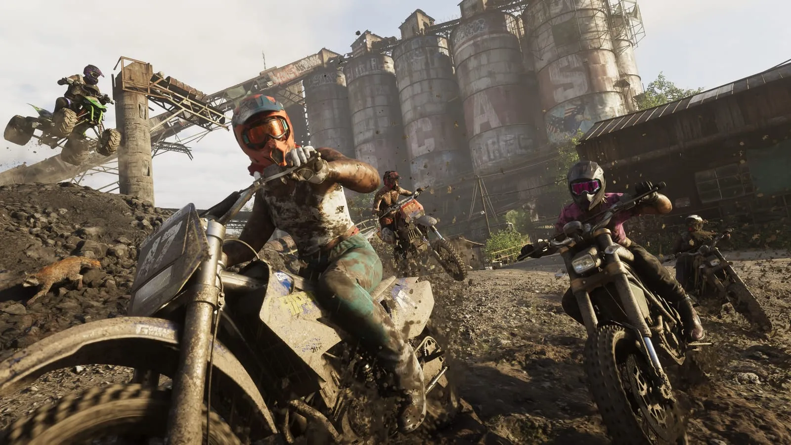 Pilotes de motocross lancés dans la boue d'une carrière devant de vieux silos industriels tagués
