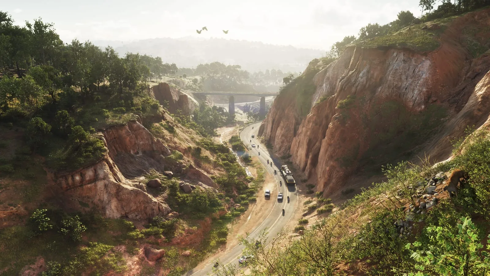 Two-lane road winding through an ochre canyon, light traffic and a highway bridge beyond