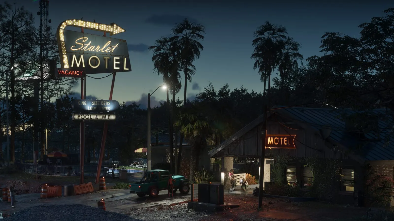 Starlet Motel neon sign glowing over a roadside parking lot at dusk, green pickup truck parked outside