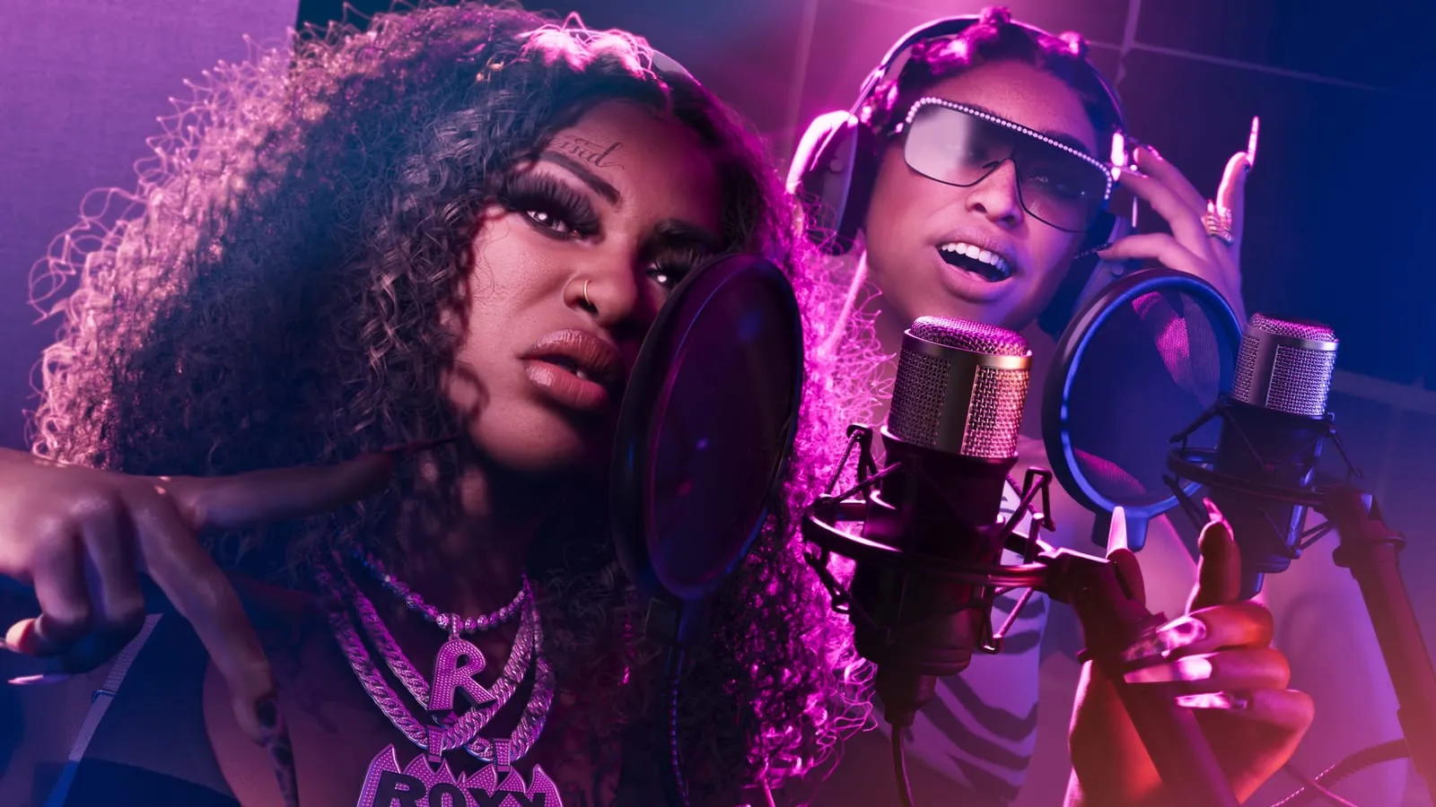 Deux chanteuses devant leurs micros dans une cabine d'enregistrement éclairée en rose