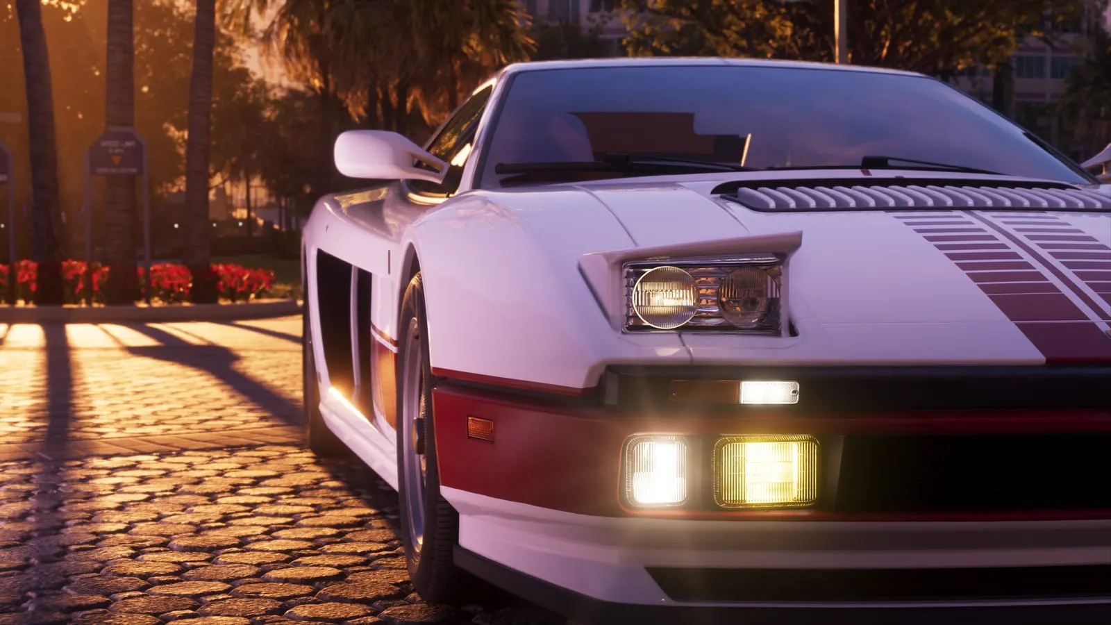 Front end of a white sports car with headlights on, golden late day light across cobblestones