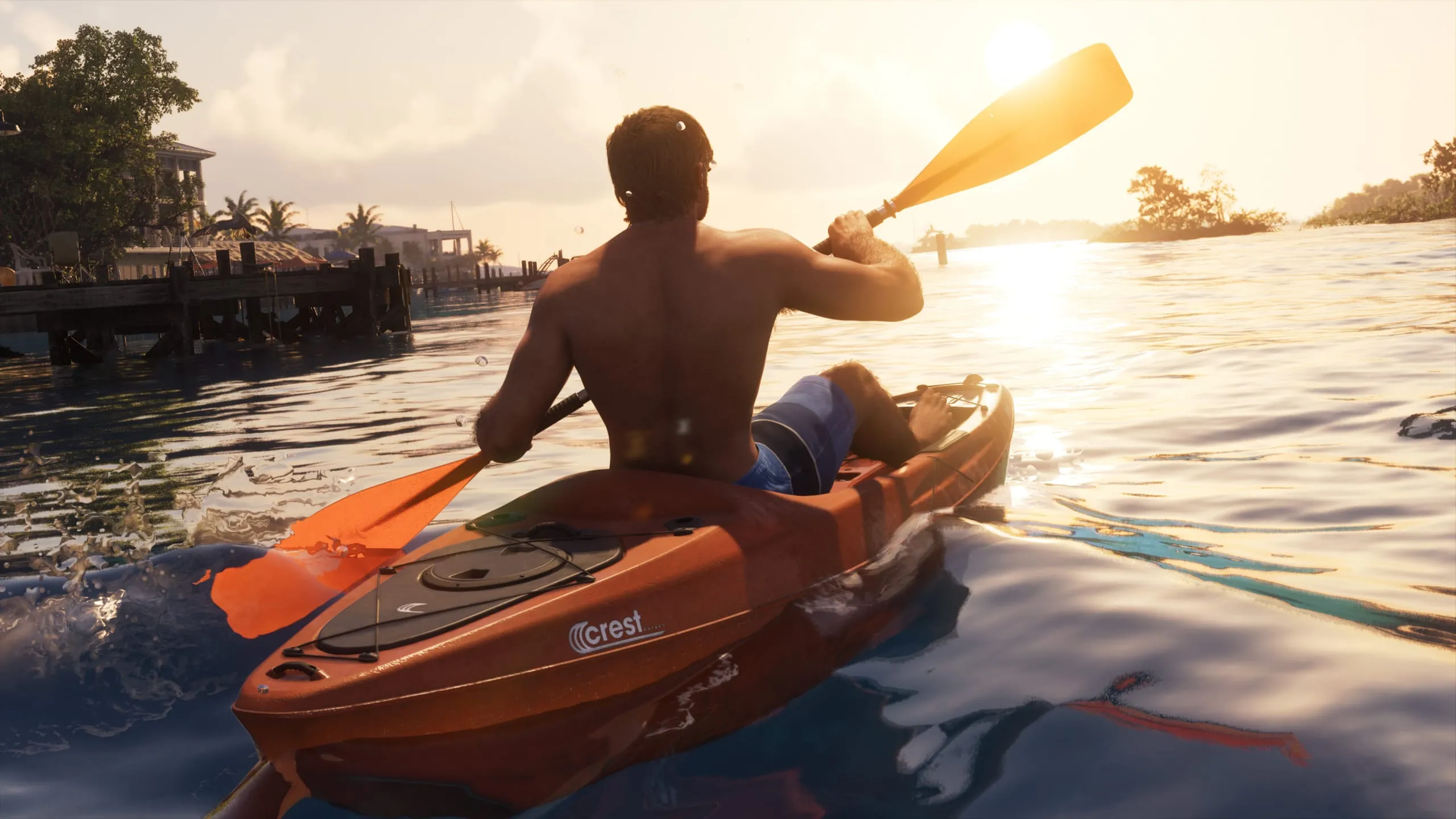 Homme torse nu pagayant un kayak orange au coucher du soleil, une personne allongée à l'avant