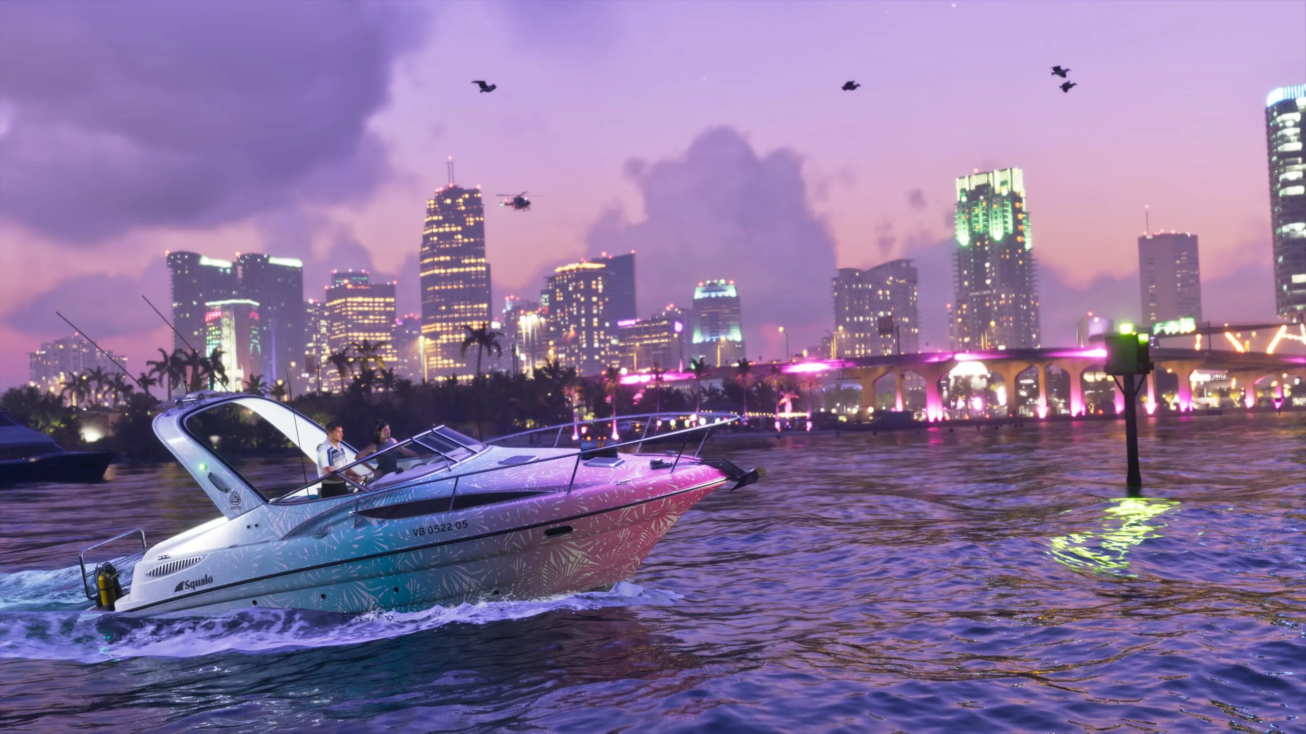 Pink and teal Squalo speedboat cutting across the bay with the lit city skyline behind