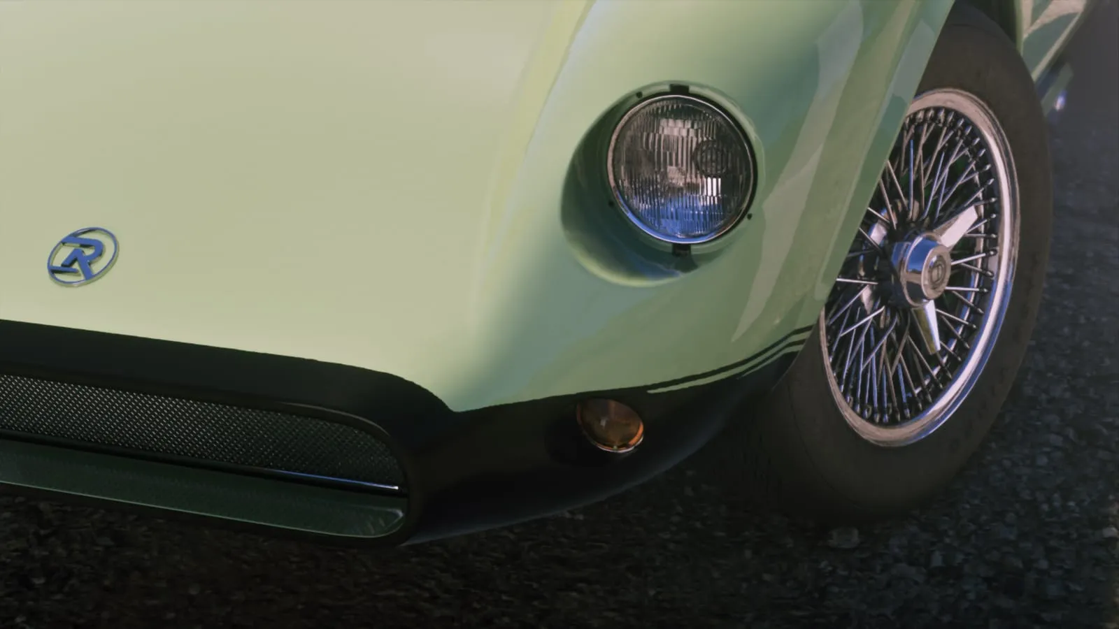 Nose of a pale green roadster: round headlight, blue R badge, chrome wire wheel