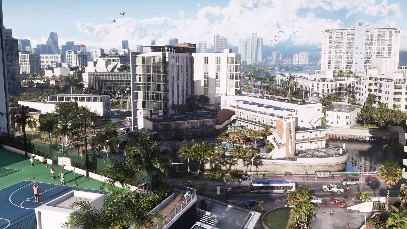 Vue aérienne d'un quartier balnéaire, terrain de basket, hôtel avec piscine et gratte-ciel au fond