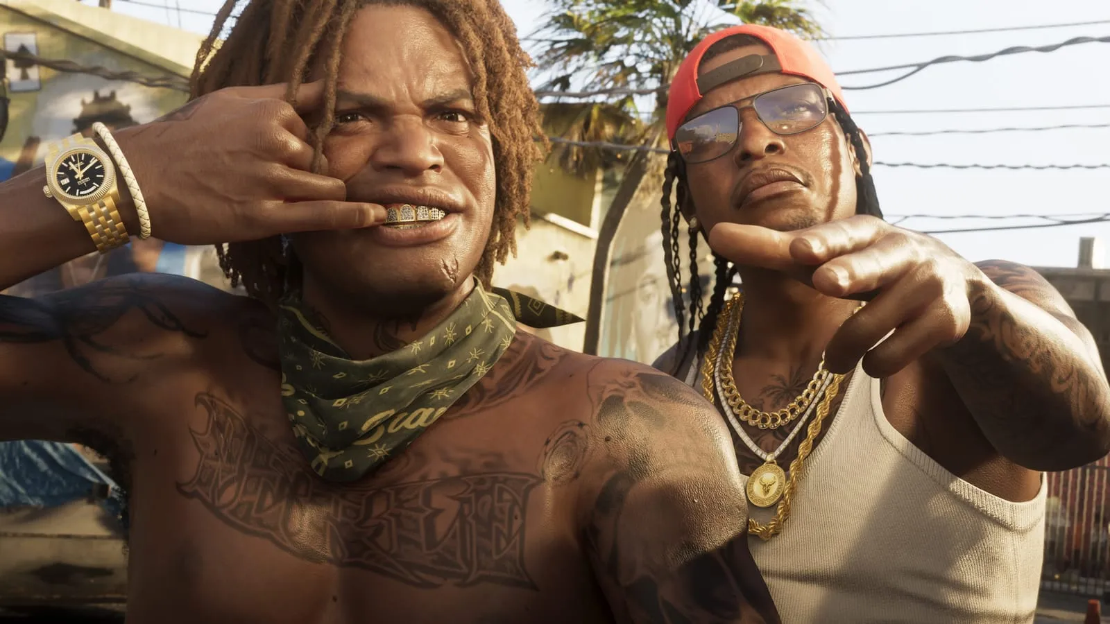 Two heavily tattooed men pose for the camera on a sunlit street, gold chains and a red cap