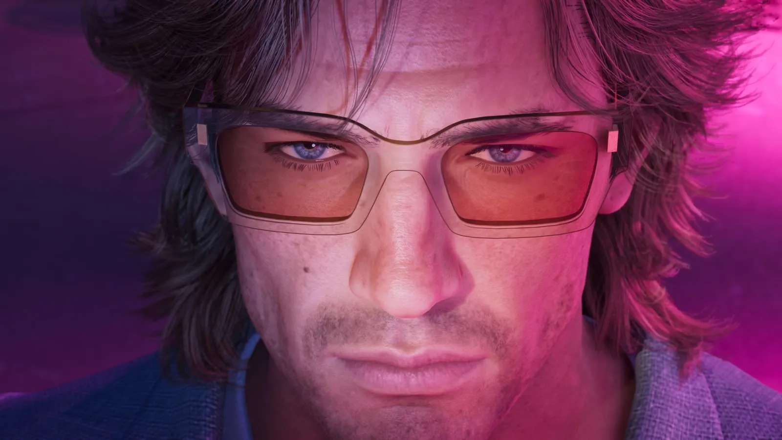 Close portrait of a man in amber-tinted glasses against a bright pink backdrop